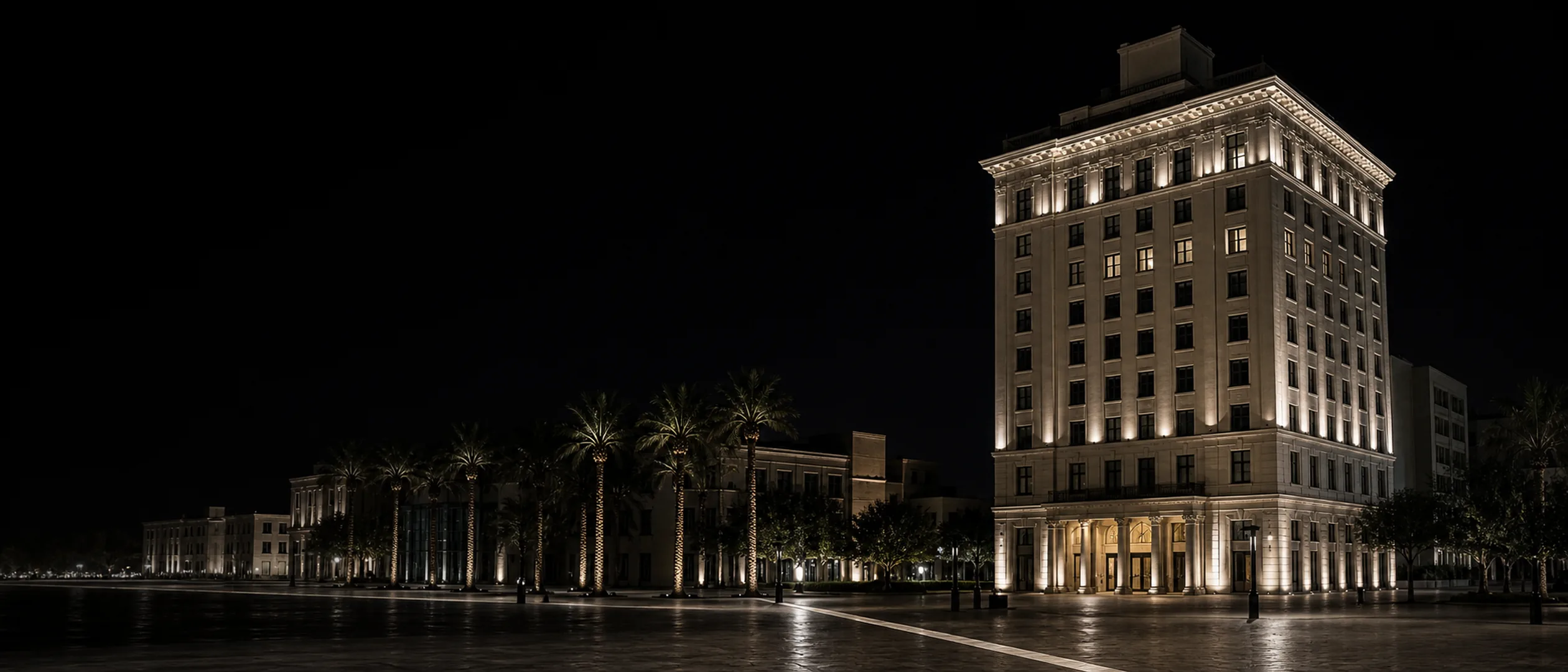 The historic Padre Hotel rises over a quiet downtown Bakersfield plaza at night.