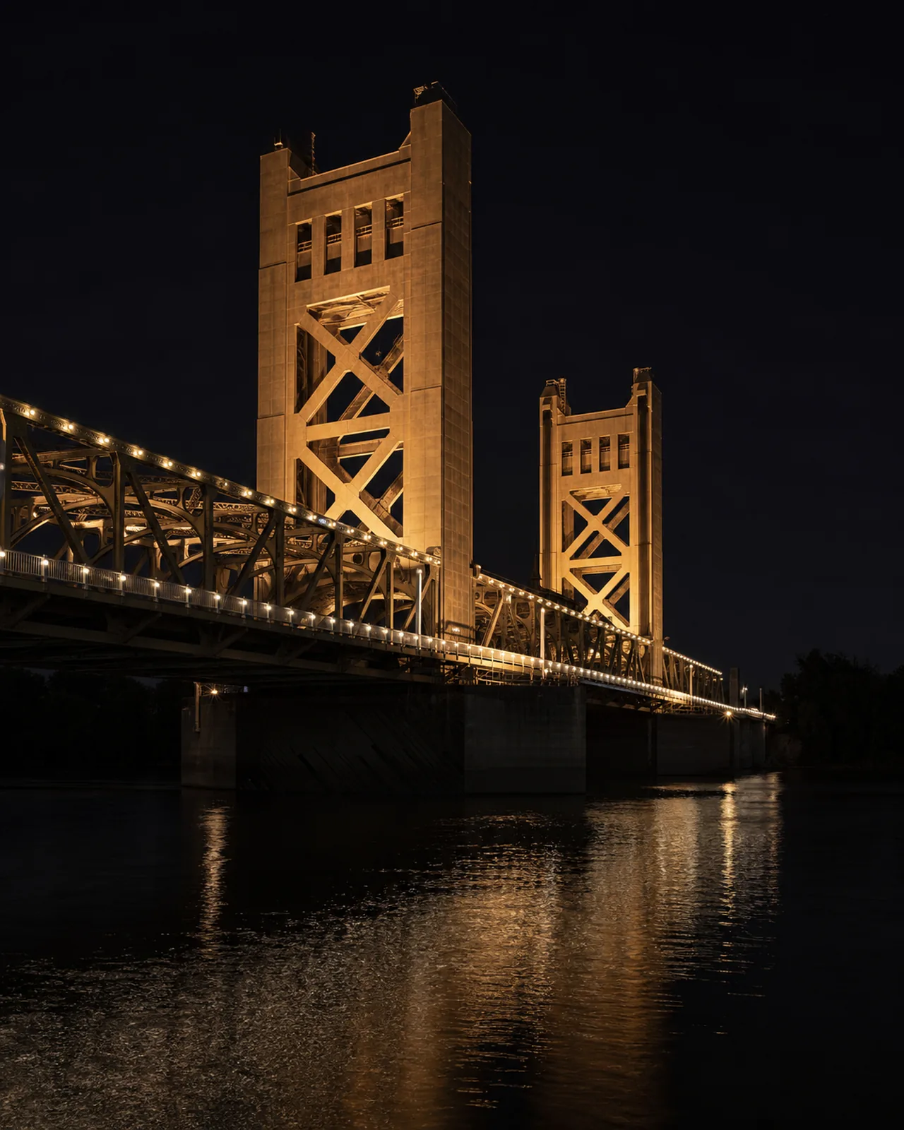 Sacramento Tower Bridge lift towers and truss reflected in the river at dusk